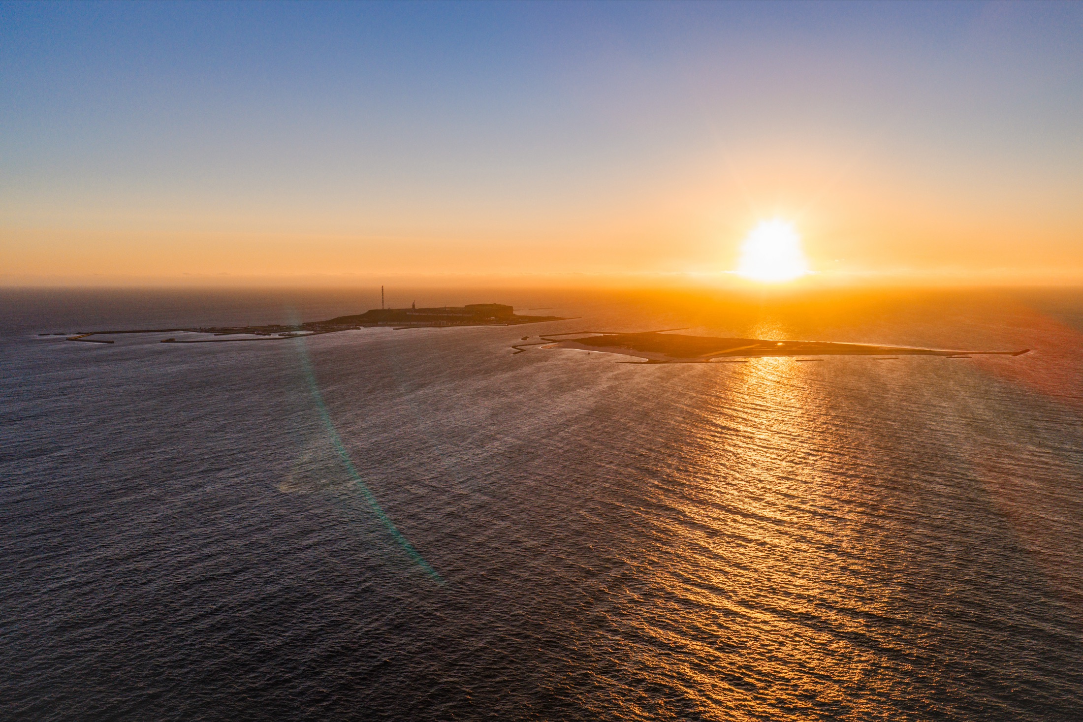 Helgoland und Düne als Silhouette im Sonnenuntergang über der Nordsee